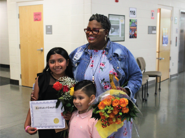 teacher posing with students and flowers